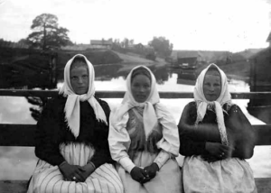 Kolme nuorta neitiä istuvat penkillä