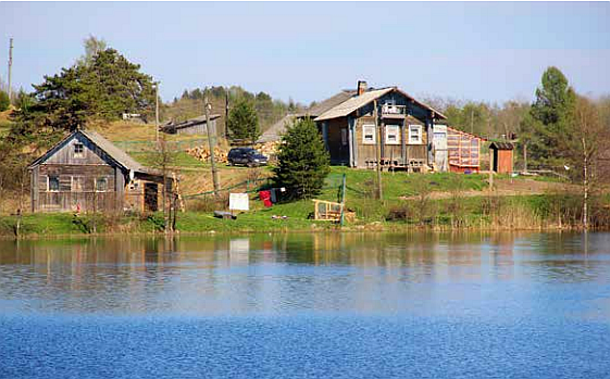 Järven rannalla kaksi puista taloa.