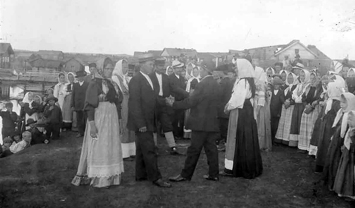 Ryhmä ihmisiä pihalla ja taustalla puutaloja