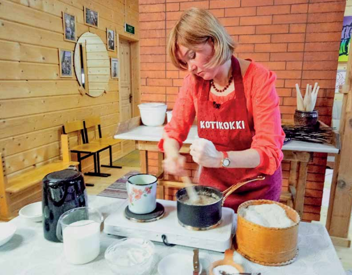 Nainen punaisessa asussa hämmentää kauhalla ruokaa keittiössä
