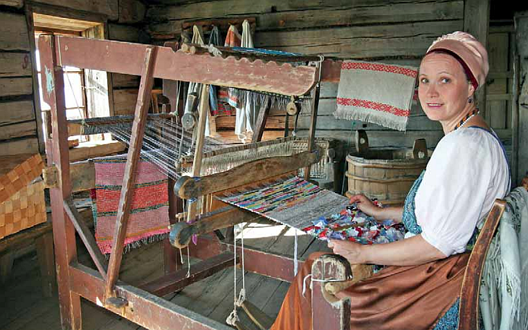 Nainen kangaspuiden edessä kutomassa