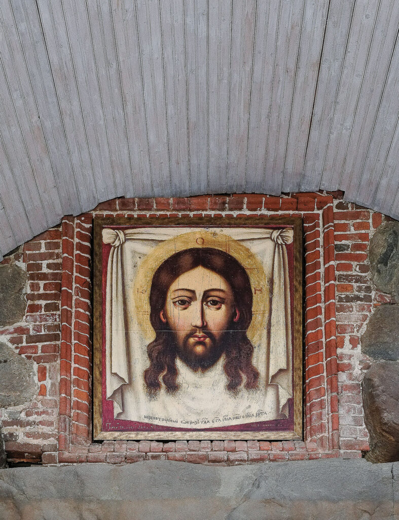 Maalaus Jeesuksen kasvoista tiiliseinällä.