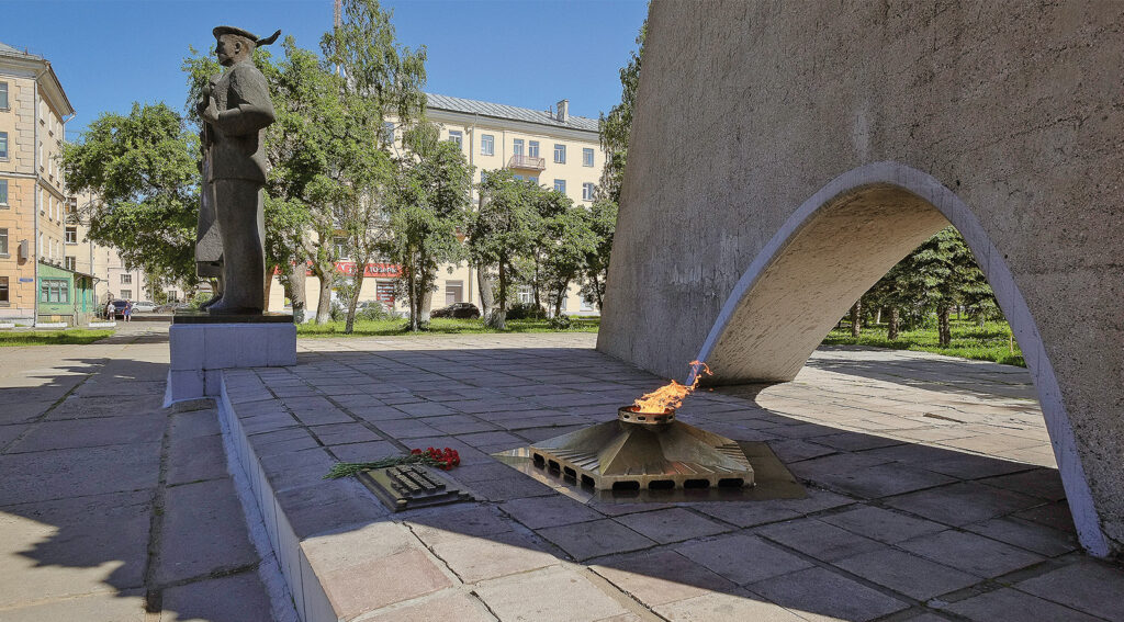 Monumentin edessä palaa tuli aurinkoisella aukiolla.