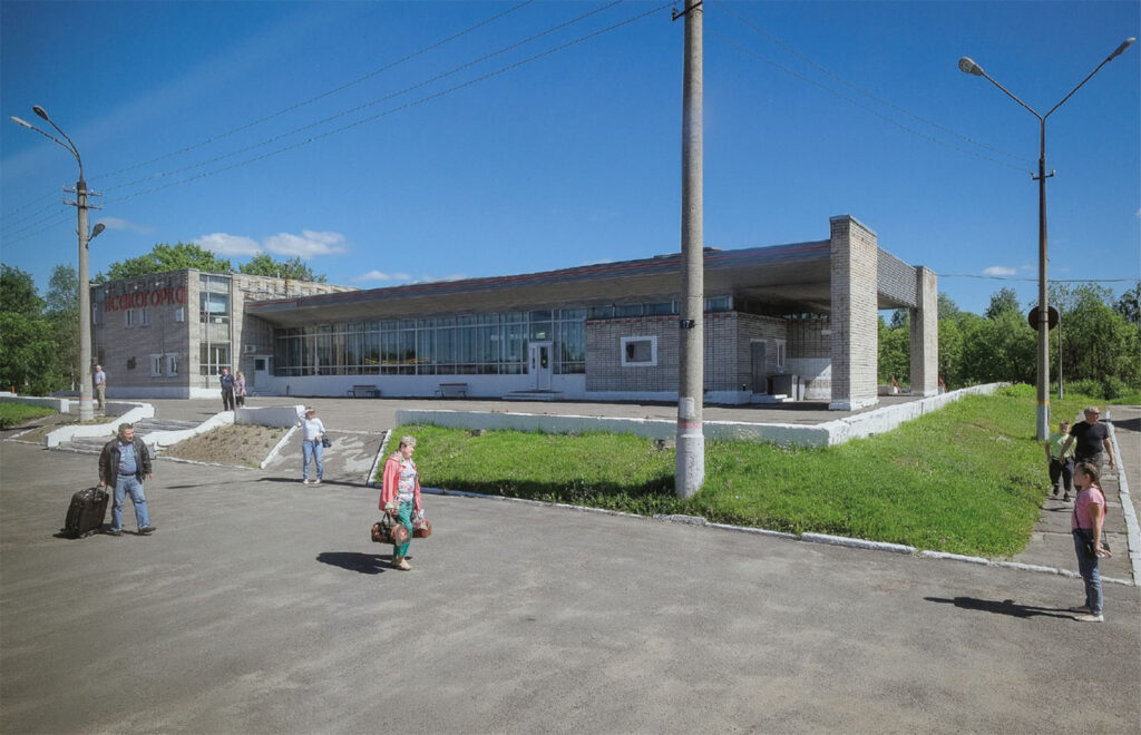 Rautatieasema ja sen edustalla muutamia ihmisiä kävelemässä laukkujen kanssa.