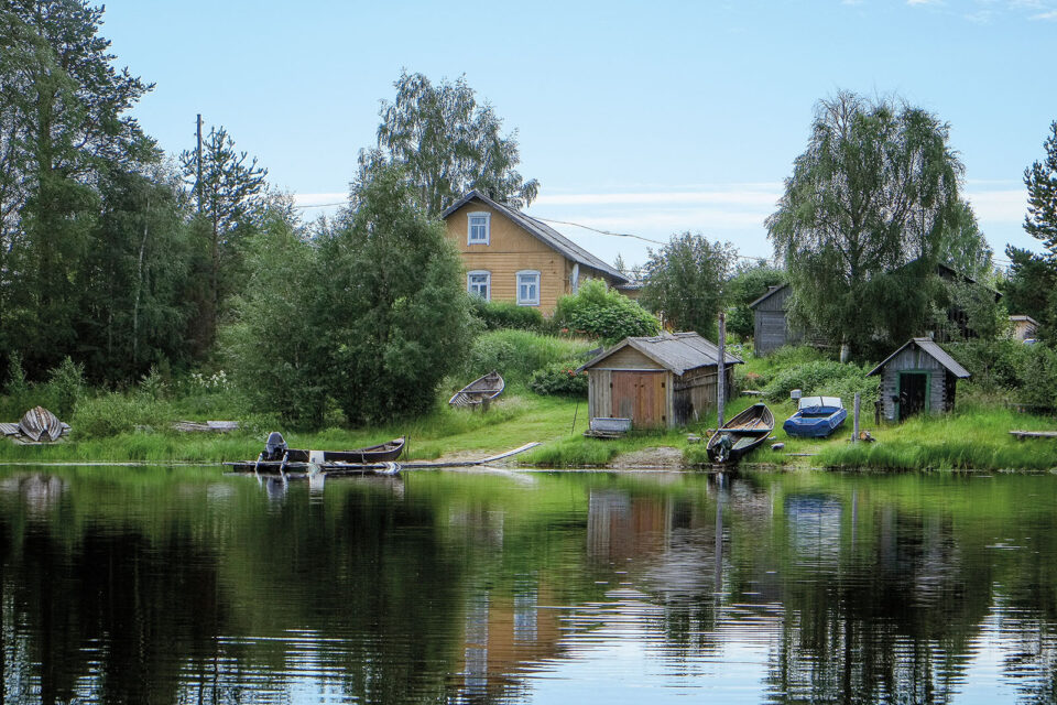 Järven rannassa talo ja vene rannassa.