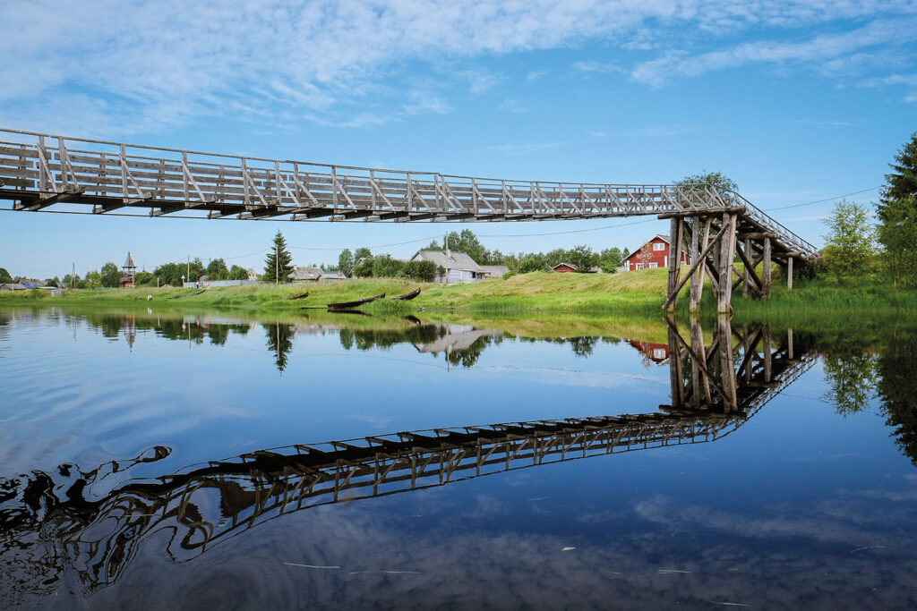 Pitkä riippusilta peilaa veteen.
