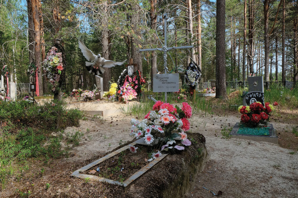 Hautausmaa, kukkia haudoilla. Taustalla mäntymetsä.