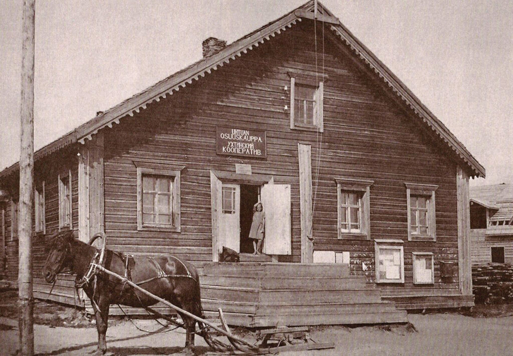 Suuri kaksikerroksinen puutalo vanhassa kuvassa.