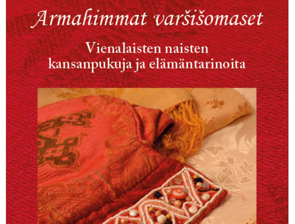 Punaisella pohjalla valokuva vanhasta, helmikuvioin koristellusta, oranssinpunaisesta vienalaisen naisen päähineestä, sorokasta. Päähineen alla on vaaleita silkkihuiveja siististi viikattuina. Kuvan yläpuolella teksti: "Armahimmat varšišomaset - vienalaisten naisten kansanpukuja ja elämäntarinoita".