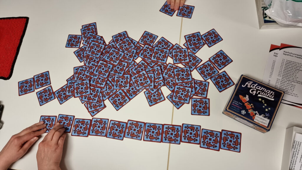 Suoraan ylhäältä päin otettu lähikuva muistipelikorteista, joita sekoitetaan ja asetellaan pöydälle pelaamista varten.