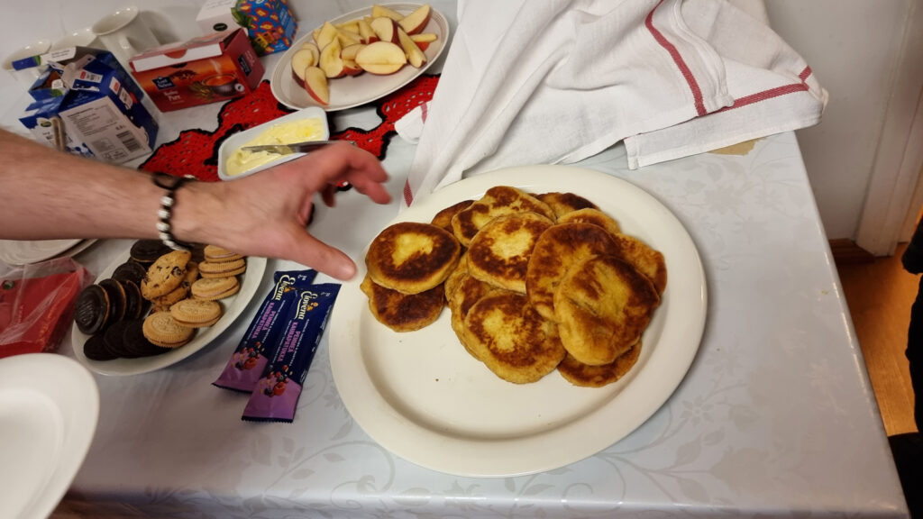 Lähikuva kädestä, joka ojentuu poimimaan tarjoiluvadilla lepääviä mehevän näköisiä lettuja.