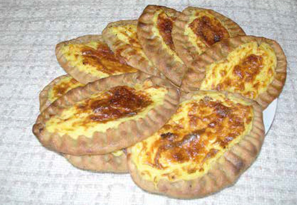 Lautasellinen vastapaistettuja, meheviksi voideltuja karjalanpiirakoita.