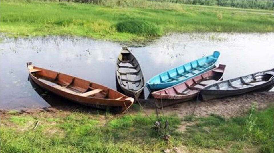 Viisi värikästä soutuvenettä on joen rannalla kokat kohti toisiaan.