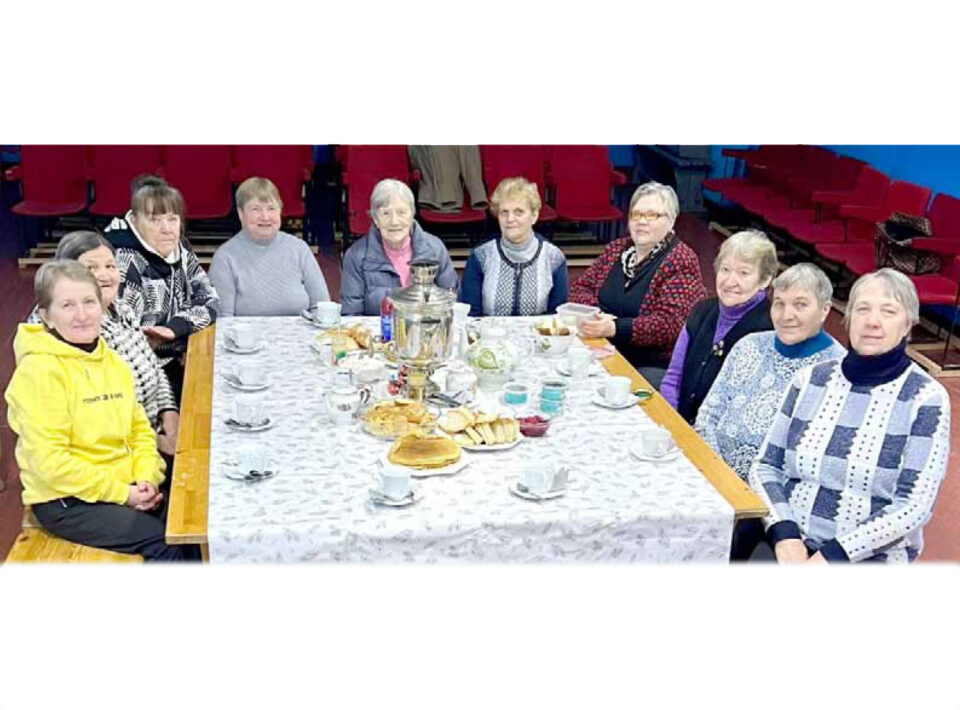 Kymmenen naista teepöydän ympärillä.