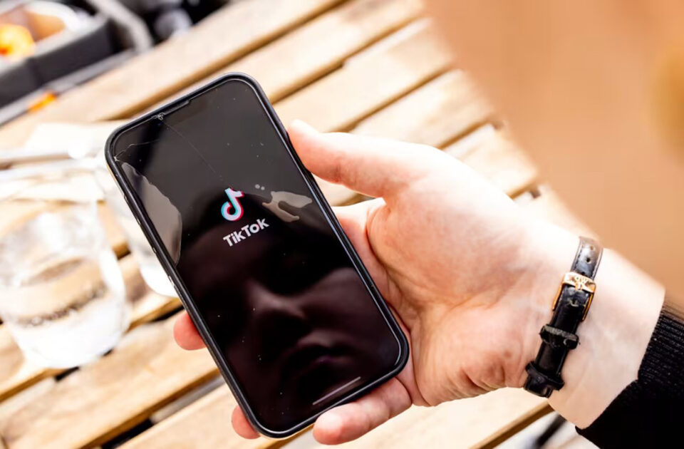 Kämmenellä matkapuhelin, jonka ruudulla TikTok-kuvake.