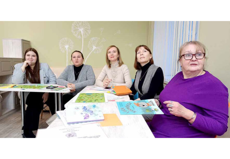 Viisi naista pöydän ympärillä kuuntelevan ja keskittyneen näköisinä, edessä kirjoja ym. materiaalia.