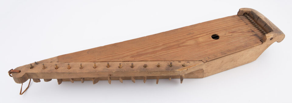 Valkoisella taustalla lähikuvassa 13-kielinen, vaaleasta puusta tehty kantele.