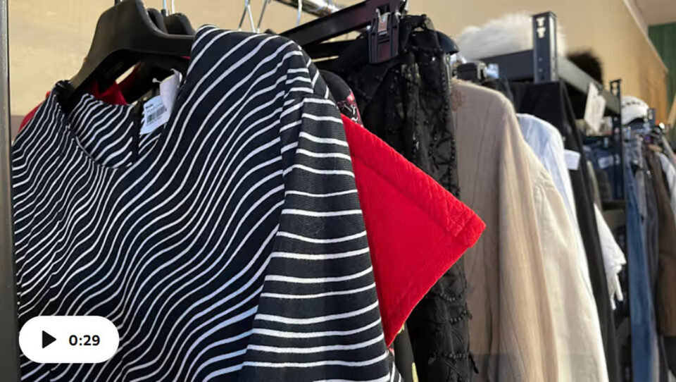 Lähikuva henkareissa roikkuvista erivärisistä ja erityylisistä vaatteista. Kuvakaappaus videolta.