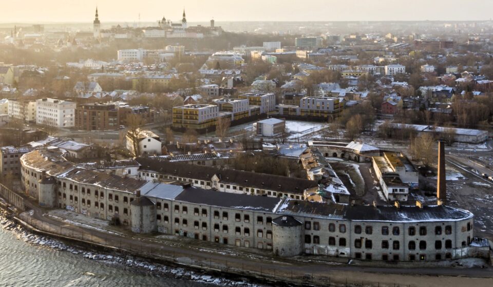 Droonilla otettu ilmakuva Tallinnan yläpuolelta, etualalla iso, kaareva, muurimainen kivirakennus