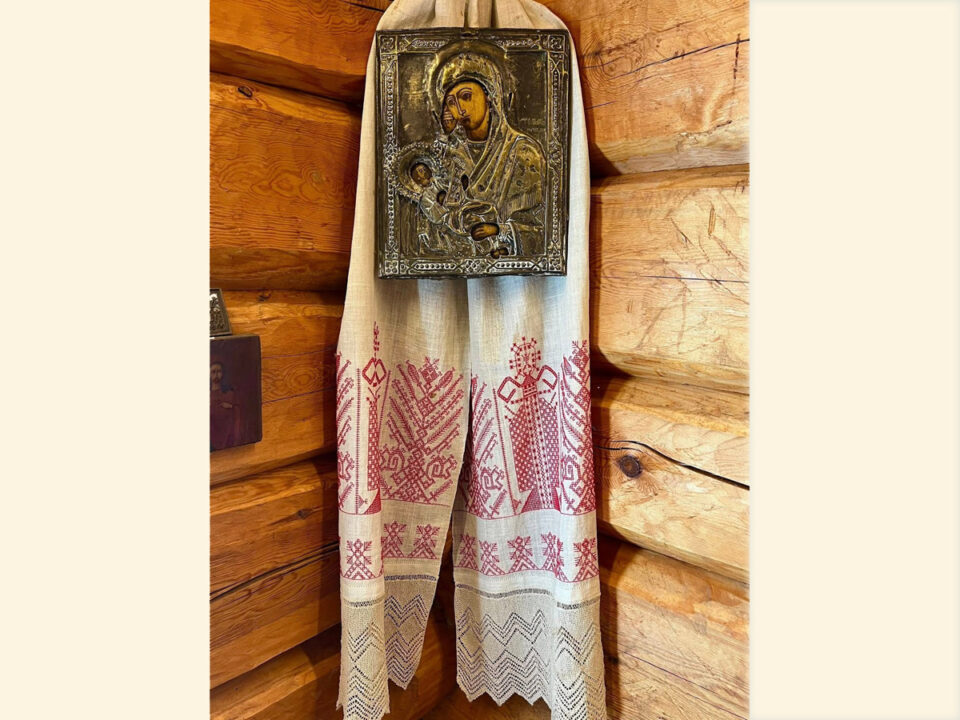 Hirsitalon sisänurkka, jossa seinällä riippuu karjalainen punakirjonnalla koristeltu, vaaleaa pellavakangasta oleva käsipaikka. Sen päälle on ripustettu Neitsyt-Mariaa ja Jeesus-lasta esittävä ikoni.