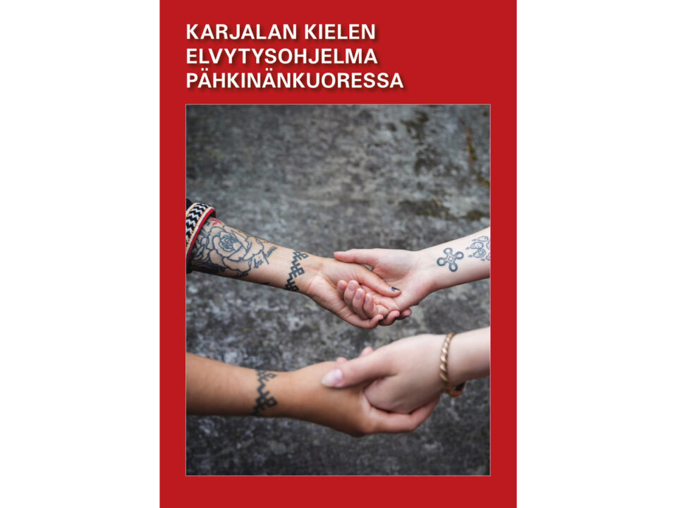 Kirkkaanpunaisella taustalla on valkoinen teksti: Karjalan kielen elvytysohjelma pähkinänkuoressa. Tekstin alapuolella on neliskanttinen kuva, jossa kahden vastakkain olevan ihmisen kädet ottavat toisistaan kiinni. Käsivarsissa ja ranteissa näkyy tatuointeja, toisella on vasemmassa ranteessaan Kalevala-korun pronssinen rannerengas.