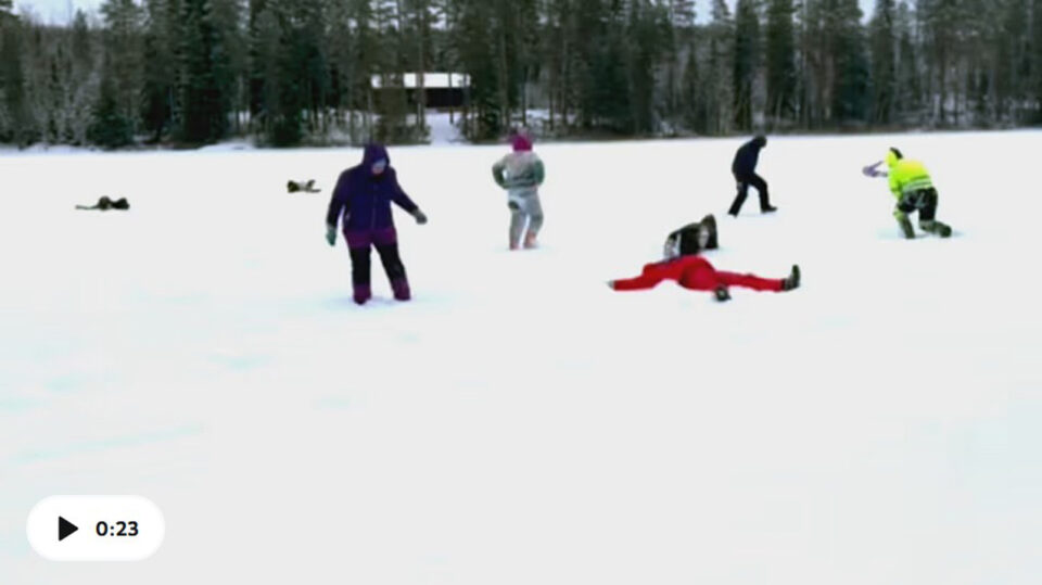 Lumisella järvenjäällä pötköttää ja liikuskelee joukko värikkäisiin ulkoiluvaatteisiin pukeutuneita ihmisiä.