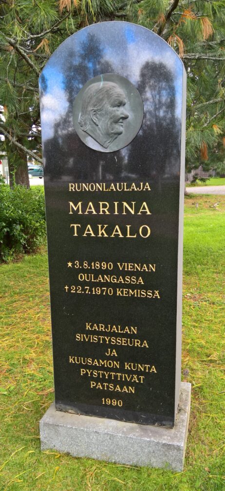Runonlaulaja Marina Takalon muistomerkki Kuusamon Opiston pihamalla, pystyttäneet Karjalan Sivistysseura ja Kuusamon kaupunki vuonna 1990. Sampo-tietokanta.