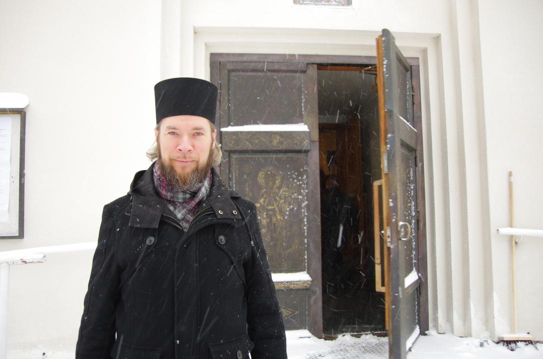 Arkkimandriitta Mikael, luostarin johtaja mustassa asussa oven edessä lumisateessa