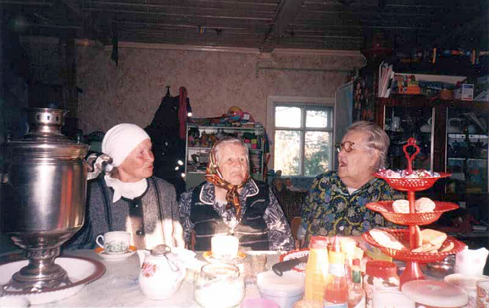 Kolme iäkästä naista istuu teepöydän äärellä
