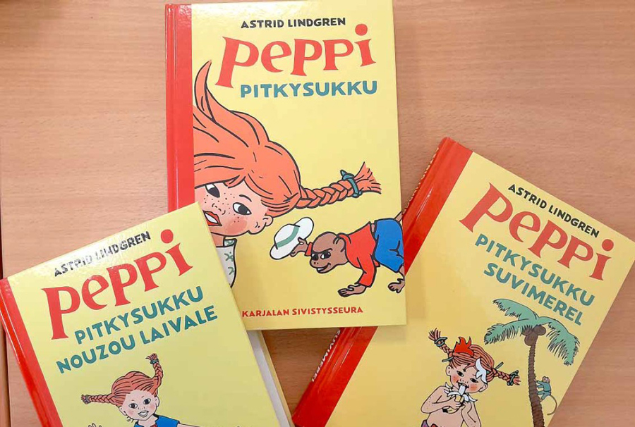Kolme livvinkarjalaksi käännettyä Peppi Pitkätossu -kirjaa lojuu pöydällä.