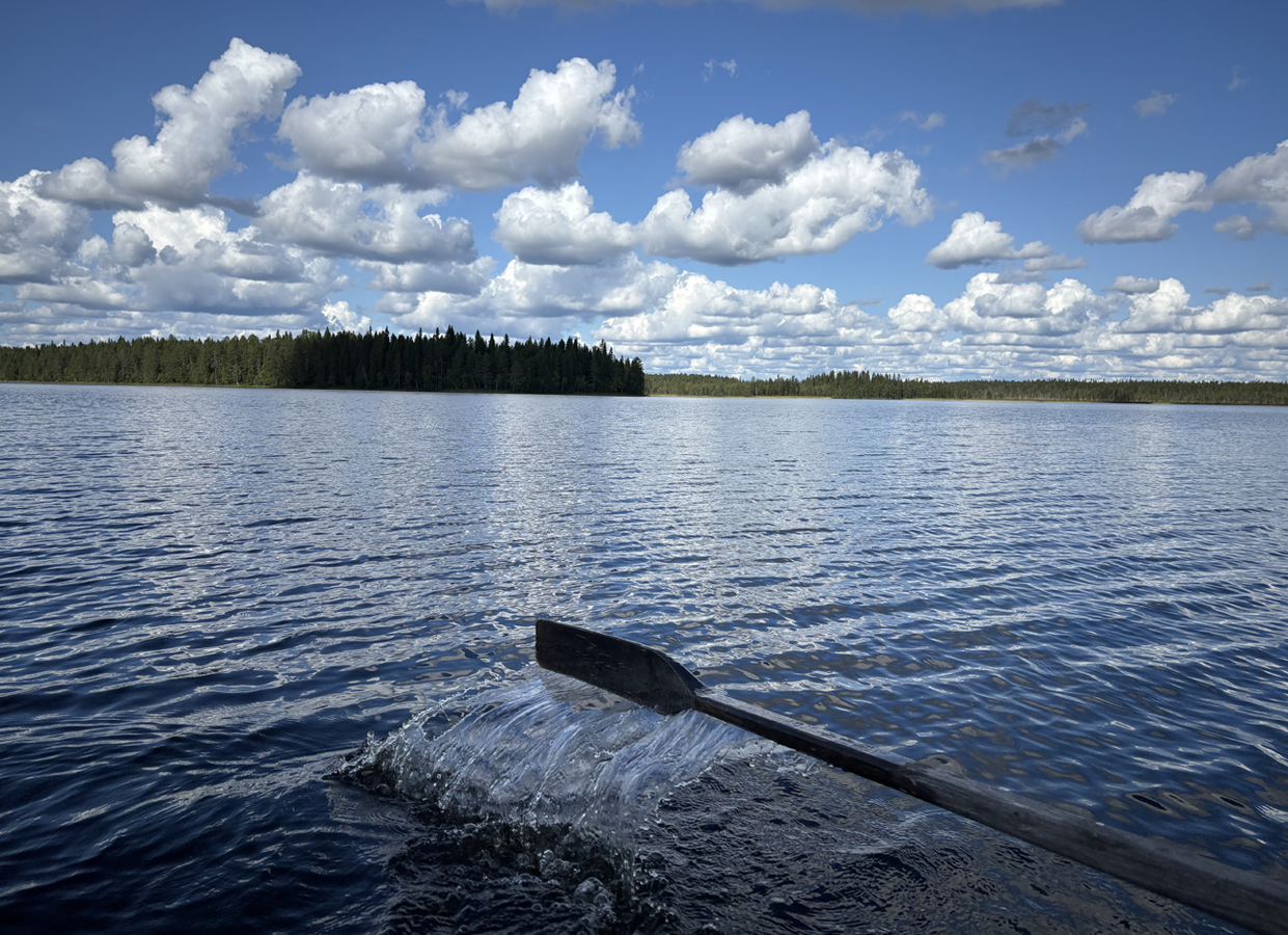 Sininen järvenselkä, sinisellä taivaalla valkoisia poutapilviä. Airo nousee vedestä, kuin olisi kuvaajan kädessä, airon lavasta roiskahtelee auringonvalossa kimaltavia suuria vesiroiskeita.